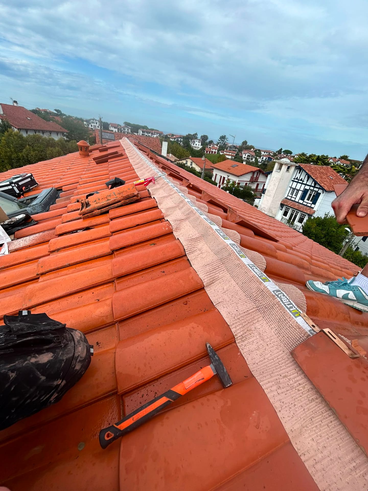 Couvreur posant un closoir de faîtage ventilé neuf lors de la réfection d'un faîtage en tuiles au Pays Basque (64)
